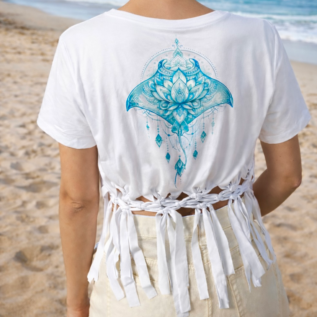 Person wearing a white t-shirt with a blue mandala manta design on the beach