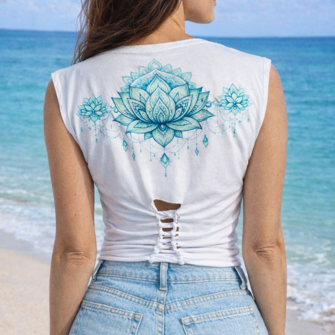 Person wearing a white sleeveless shirt with blue lotus flower design on a beach.